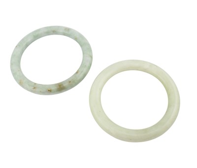 Lot 219 - Two green jade bangles. Internal diameter...