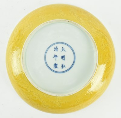 Lot 130 - HONGZHI MARKED INCISED YELLOW GLAZED DRAGON CHARGER 大明弘治款黄地暗花龙纹盘